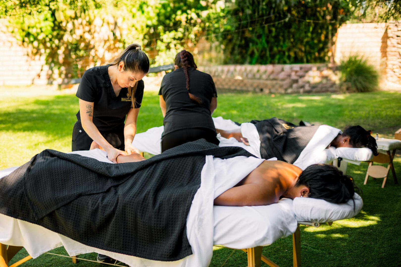 People receiving outdoor massages on tables in a serene setting.
